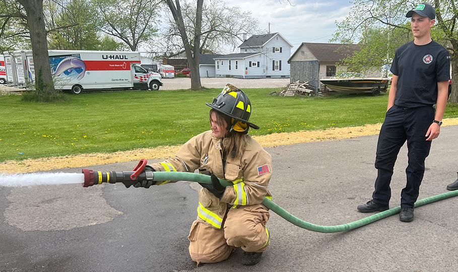 Job shadow, girl practicing using hose with firefighters